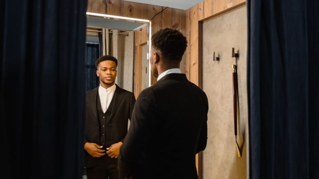 Man in a well-fitted suit checking his outfit in a mirror